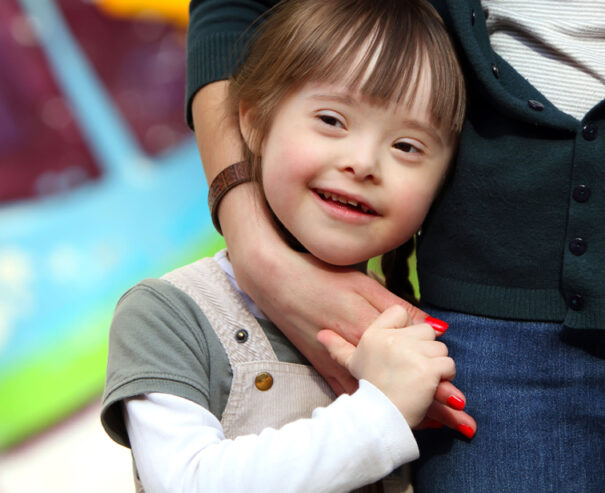 Portrait d'une enfant souriante entourée du bras de son accompagnatrice